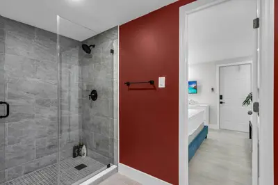 a bathroom with a shower with a red wall at La Pergola Villa 7 BR PoolHot Tub Location in Miami