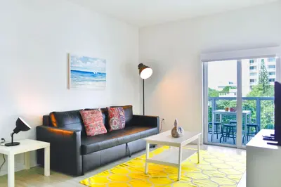 a living room with a black leather couch and a balcony at Contemporary Condo in Wynwood w Free Parking in Miami