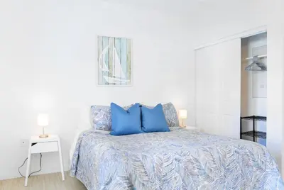 a white bedroom with a bed with blue pillows at Contemporary Condo in Wynwood w Free Parking in Miami