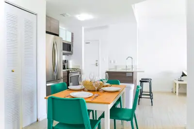 a kitchen and dining room with a wooden table and green chairs at Contemporary Condo in Wynwood w Free Parking in Miami