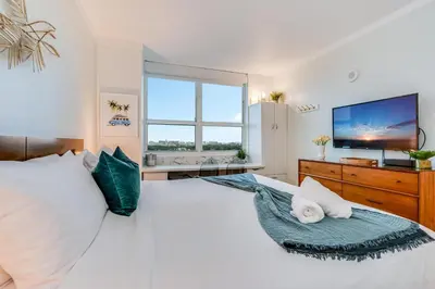 a bedroom with a large white bed with a large window at Stylish Studio King Bed City View Hotel Perks Parking in Miami