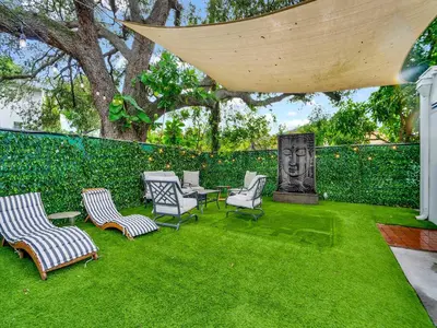 a patio with chairs and a table on grass at Casa Verde Design District 5BR Hot Tub in Miami