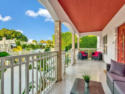 an outdoor balcony with a purple couch and chairs at Villa Ciao Bella Sleeps 25 Pool Hot Tub in Miami
