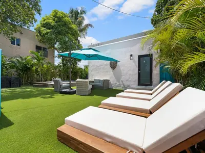 a patio with an umbrella and a lawn at Villa mi Amor Walkable Pool & Games in Miami