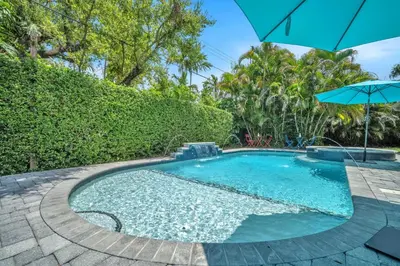 a swimming pool with an umbrella in a yard at Shady Palms - Pool & Jacuzzi in Fort Lauderdale