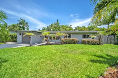 a white house with palm trees in the yard at Shady Palms - Pool & Jacuzzi in Fort Lauderdale