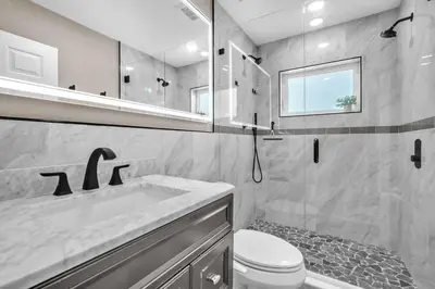 a bathroom with a sink and a toilet and a mirror at Shady Palms - Pool & Jacuzzi in Fort Lauderdale