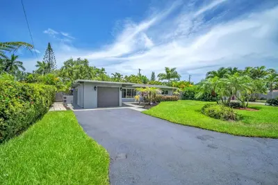 a house with a driveway in front of a yard at Shady Palms - Pool & Jacuzzi in Fort Lauderdale
