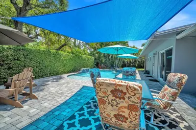 a patio with a table and chairs and an umbrella at Shady Palms - Pool & Jacuzzi in Fort Lauderdale