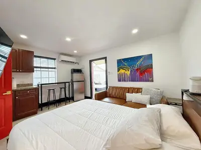 a bedroom with a large white bed and a kitchen at Cottage with Hot Tub, Private Firepit, Entrance, Parking BBQ in Miami Gardens