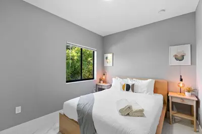 a bedroom with a bed with white sheets and a window at Stylish Townhouse Steps from Wynwood in Miami