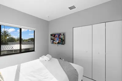 a white bedroom with a bed and a window at Stylish Townhouse Steps from Wynwood in Miami
