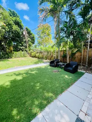 a yard with two black chairs in the grass at North Miami Vacation Home in North Miami Beach