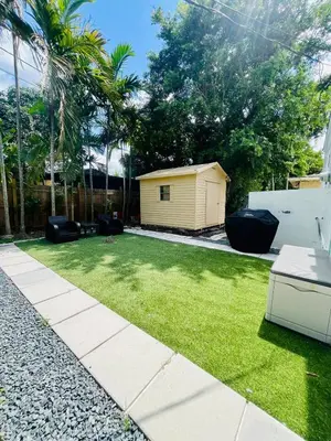 a garden with a small yellow shed in the background at North Miami Vacation Home in North Miami Beach