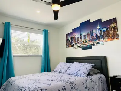 a bedroom with a bed with blue curtains and a window at Villa Las Olas Designed with you in mind! in Fort Lauderdale