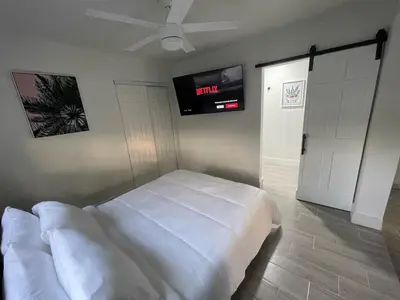a bedroom with a bed and a tv on the wall at The Vice City Suite - Private stay with Free Parking in the Heart of Miami in Miami
