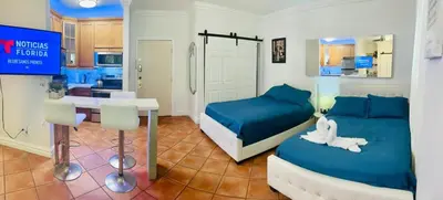 a bedroom with two beds and a table and a kitchen at south beach apartment 5 min walk to the ocean in Miami Beach