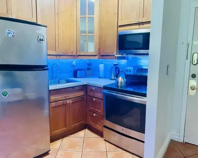 a kitchen with wooden cabinets and a stainless steel refrigerator at south beach apartment 5 min walk to the ocean in Miami Beach