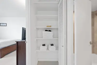 a bathroom with white towels and shoes on shelves at 1BED Condo w/Pool View | 3rd Floor at Tides in Hollywood