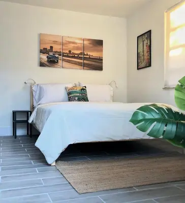 a bedroom with a white bed with two paintings on the wall at The Havana Nights Guesthouse - Private Stay with Free Parking in the Heart of Miami in Miami
