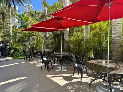 a group of tables and chairs with red umbrellas at Luxury Ocean View Apartment 1208 Hallandale Beach in Hallandale Beach
