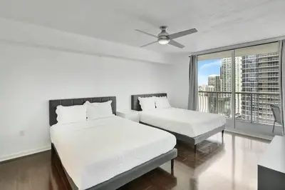 a white bedroom with two beds and a window at Newly Renovated 1BR APT with Pool, Gym, and WFH in Miami