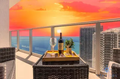 a table with a bottle of wine and glasses on a balcony at Hollywood Oceanfront Apt in Hollywood