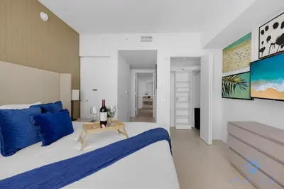 a bedroom with a bed with blue pillows and a table at Hollywood Oceanfront Apt in Hollywood
