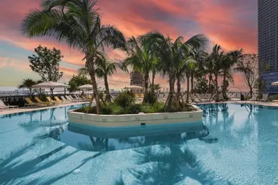 a large swimming pool with palm trees and a sunset at Beautiful Studio with Private Balcony Gym & Pool in Miami