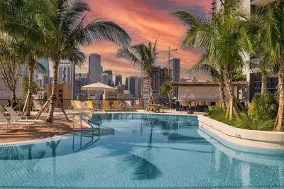 a large pool with palm trees and a city skyline at Beautiful Studio with Private Balcony Gym & Pool in Miami