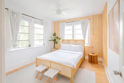 a bedroom with a bed with white sheets and windows at Designer 2BR Condo, 5 Mins to Sand, Free Parking in Hollywood