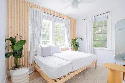 a white bedroom with a bed and a window at Designer 2BR Condo, 5 Mins to Sand, Free Parking in Hollywood