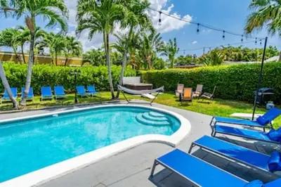 a swimming pool with blue chairs and palm trees at 437 NE 107th · Pool Hot Tub Patio 5 Bedrooms 3 BathsParking in Miami Shores