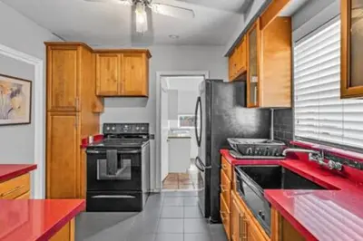 a kitchen with a black refrigerator and wooden cabinets at 427 NE 107th Studio · 6BR 3BA 7 Beds Pool Parking 2 Kitchen in Miami Shores