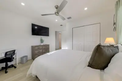 a white bedroom with a bed and a desk at 3 Mi to Hard Rock Stadium Retreat with Private Yard in Miramar