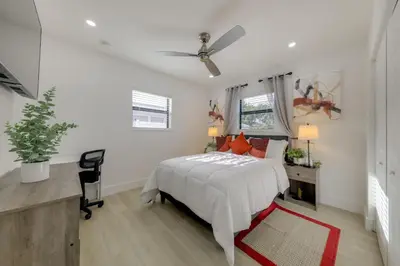 a white bedroom with a bed and a desk at 3 Mi to Hard Rock Stadium Retreat with Private Yard in Miramar