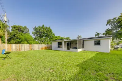 a small white house in a yard with a fence at 3 Mi to Hard Rock Stadium Retreat with Private Yard in Miramar