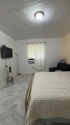 a white bedroom with a bed and a window at The Studio 6 Little Havana Walk to Marlins Stadium in Miami