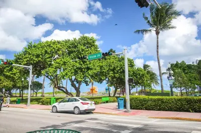 a white car parked at an intersection with a street sign at Ocean Drive Apt with Balcony & Rooftop Pool in Miami Beach