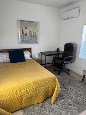 a bedroom with a bed and a desk and a chair at Charming Historic Home with Modern Comforts in Opa-locka