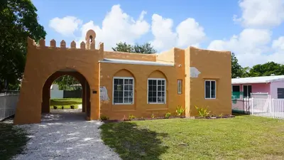 a building with an arch in a yard at Charming Historic Home with Modern Comforts in Opa-locka