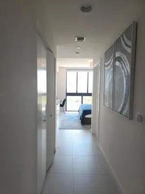 a hallway with white walls and a room with a bed at Sweetie Doral studio in Miami