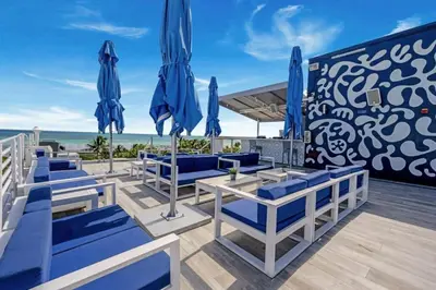 a deck with blue chairs and umbrellas on the beach at Spacious APT on South Beach Roof Top Pool & Bar in Miami Beach
