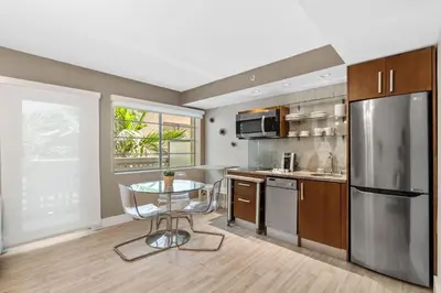 a kitchen with a table and a stainless steel refrigerator at Modern Studio in the Heart of South Beach in Miami Beach