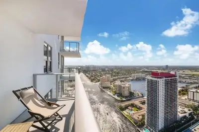 a chair on a balcony with a view of a city at Luxury Corner Apartment in Hollywood Beach in Hollywood