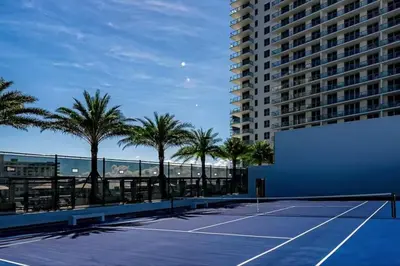 a tennis court with palm trees and a building at Luxury Corner Apartment in Hollywood Beach in Hollywood
