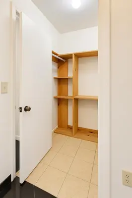 a room with white walls and a closet with wooden shelves at Stylish Wynwood studio in Miami