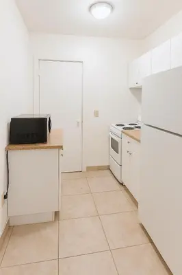 a kitchen with white appliances and white cabinets at Stylish Wynwood studio in Miami