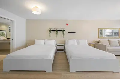 two white beds in a room with a couch at Heart of Ocean Drive - Studio - Rooftop Pool in Miami Beach