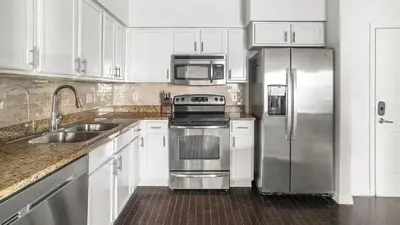 a kitchen with white cabinets and a stainless steel refrigerator at Landing Apartments - Fort Lauderdale in Fort Lauderdale